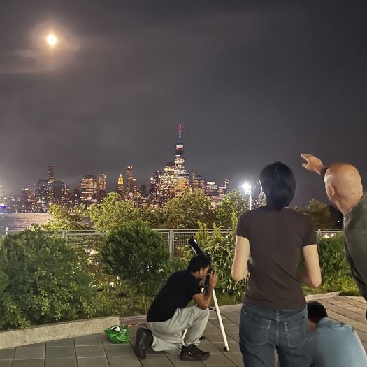 Ting Lu with telescope overlooking Manhattan