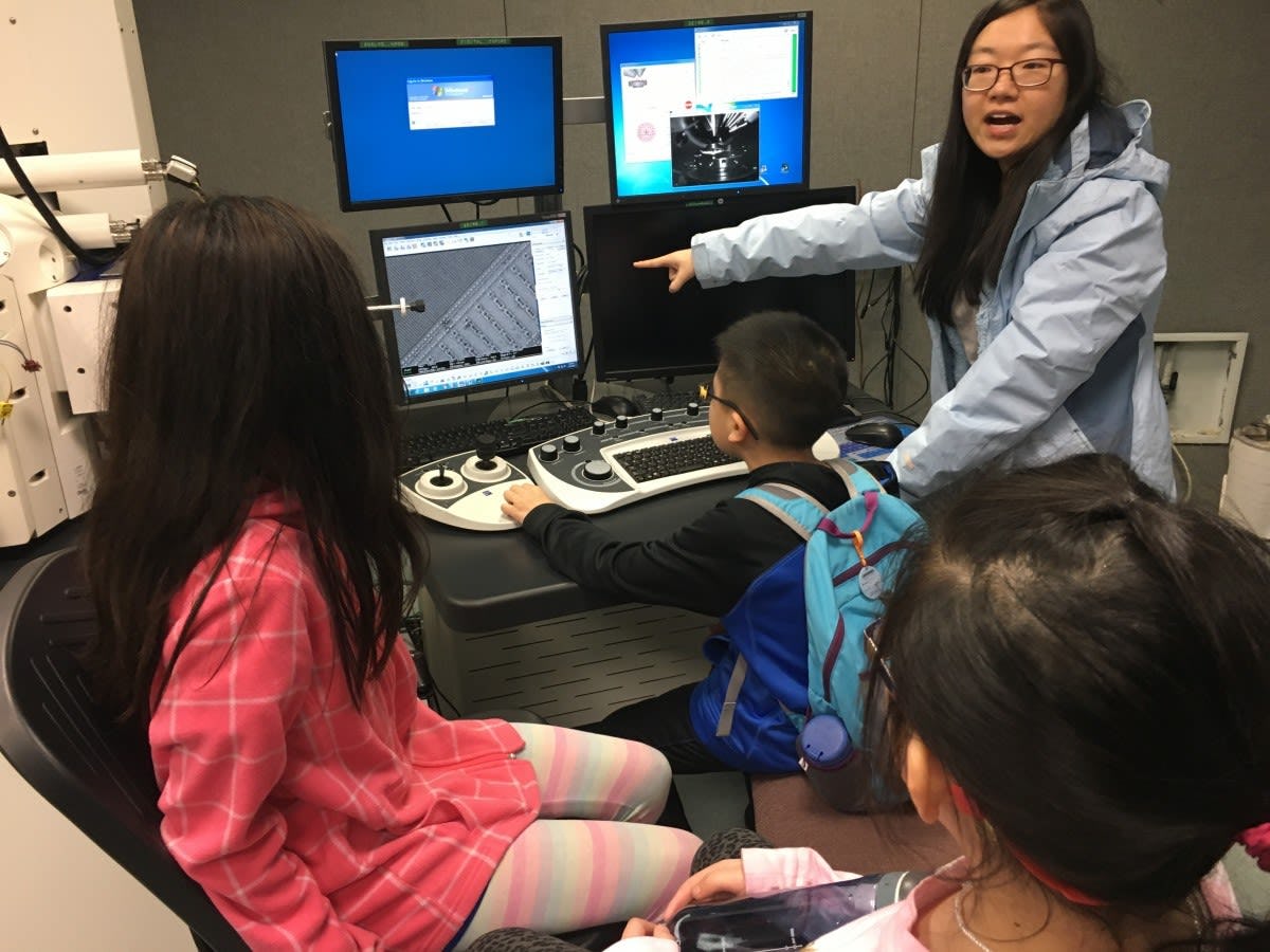 Chemical engineering Ph.D. student Xiaoquing Kong shows younger CAA students images in the Lab for Multiscale Imaging
