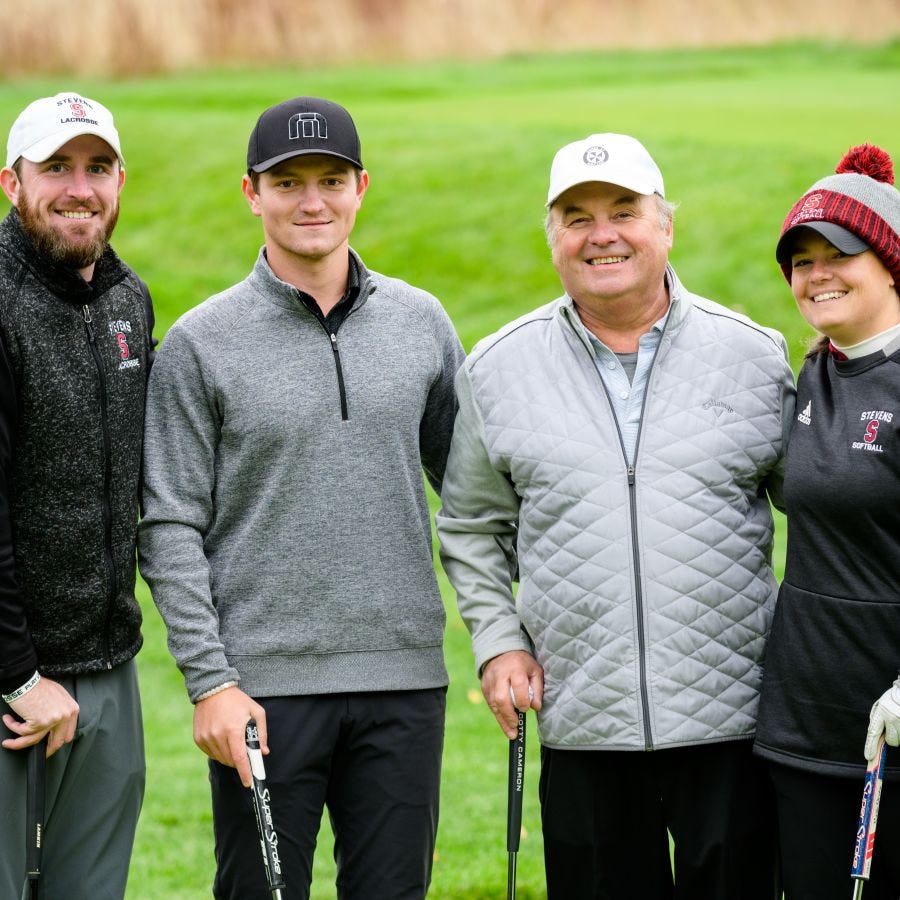 Four Stevens alumni gather on a course to play golf
