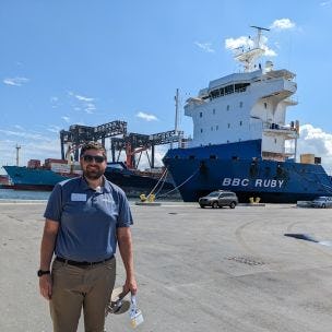 Sean Dirscherl stands in front of a cargo ship