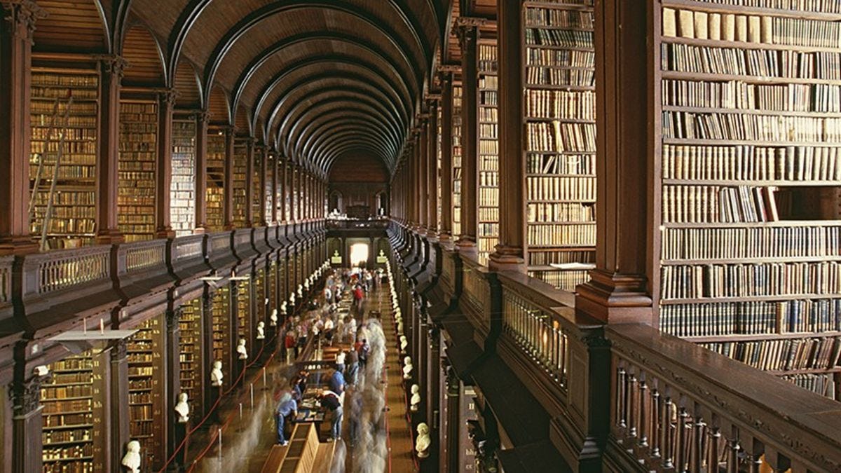 The Long Room at Trinity College, with rows of books and students studying.