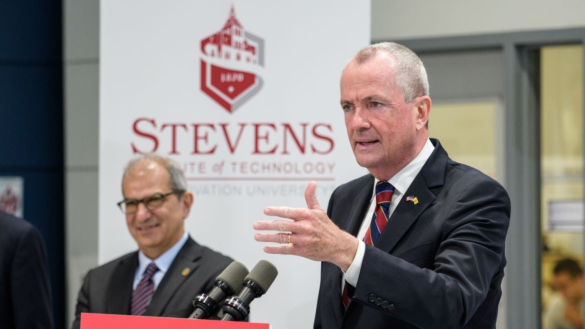 Gov. Phil Murphy speaking at the podium in the ABS  Engineering Center at Stevens Institute of Technology as President Nariman Farvardin looks on
