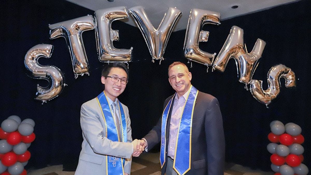Photo of student Christopher Liu with associate dean Brian Rothschild at the Beta Gamma Sigma induction ceremony.