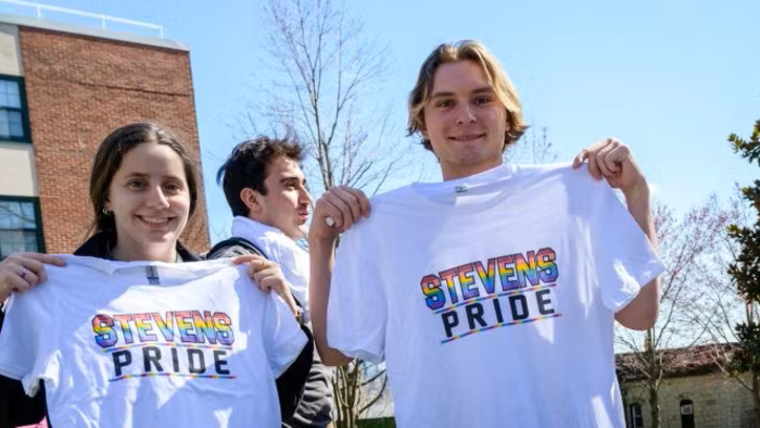 Two individuals hold tshirts with Stevens Pride written on them