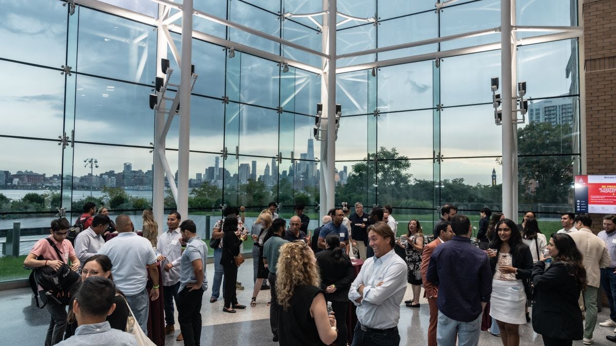 Photo of networking reception with the New Your City skyline in the background.