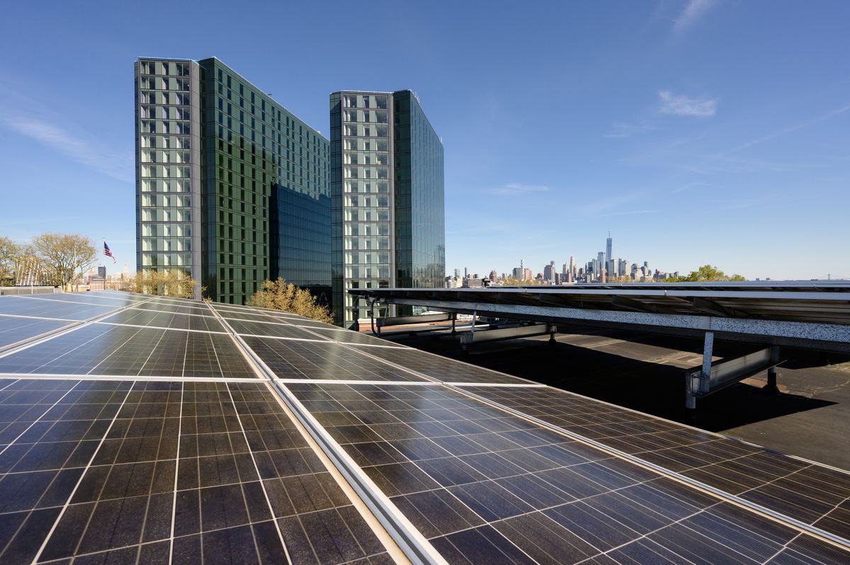 Solar panels on Stevens campus with the city skyline and two residential towers in the background