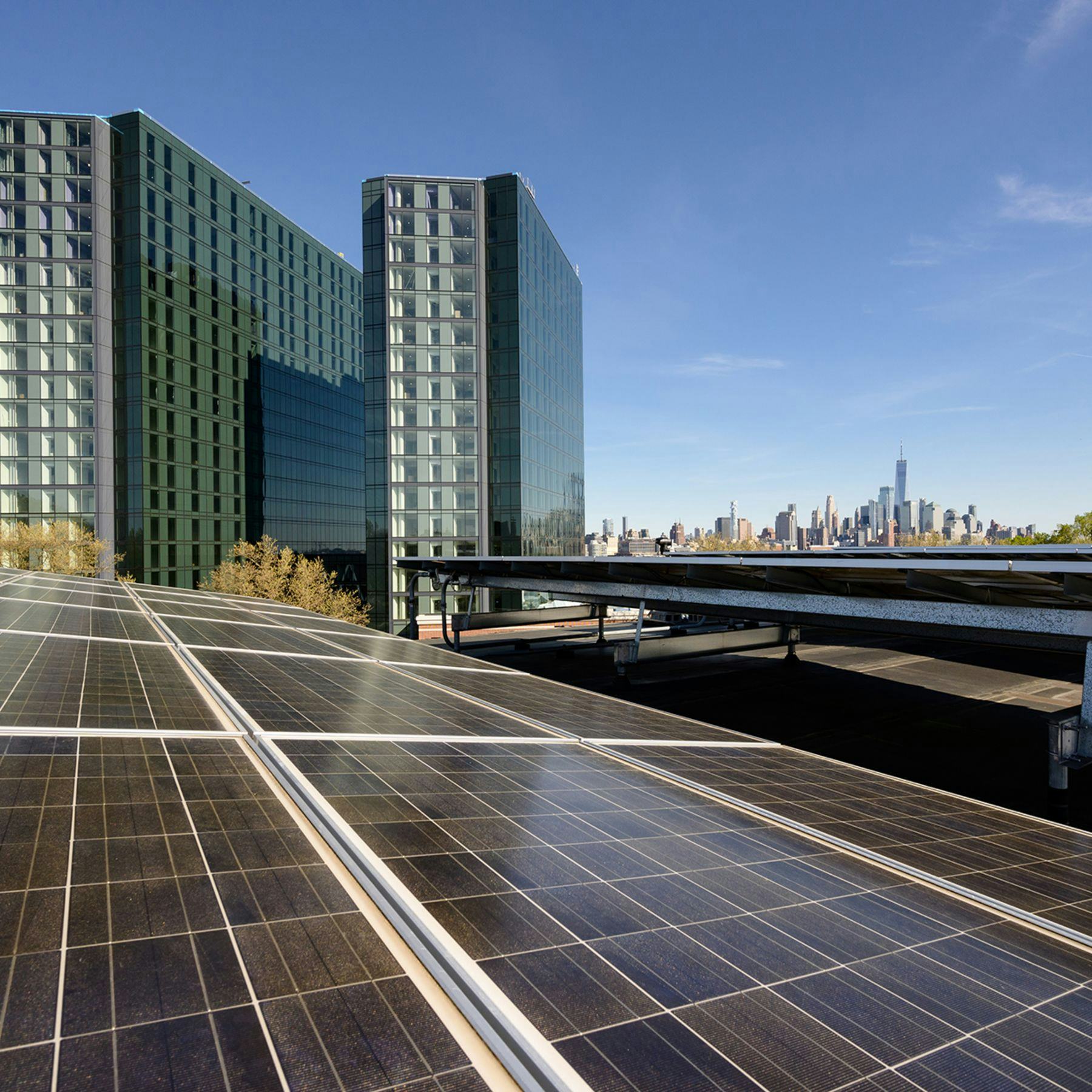 Solar panels on Stevens campus with the city skyline and two residential towers in the background