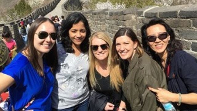 Five people smiling and standing on the Great Wall of China