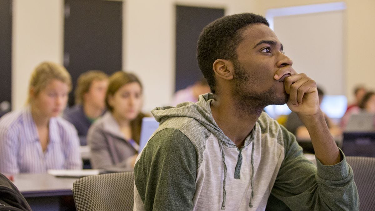 Student listens to instructor, thoughtfully