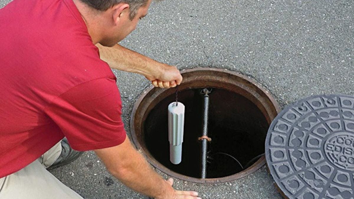 man inserting the Eastech Flow Control iTracker sensor into a manhole
