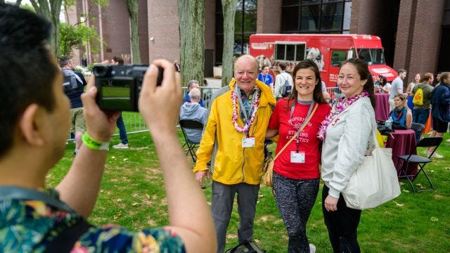 Three individuals smile while posing for a picture at Alumni Weekend