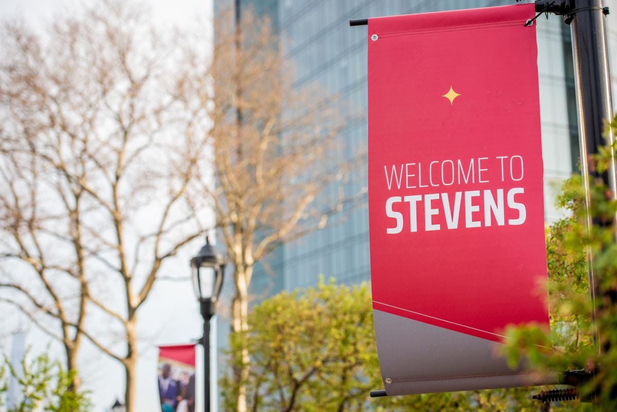 Red Welcome to Stevens banner on lamp post on campus
