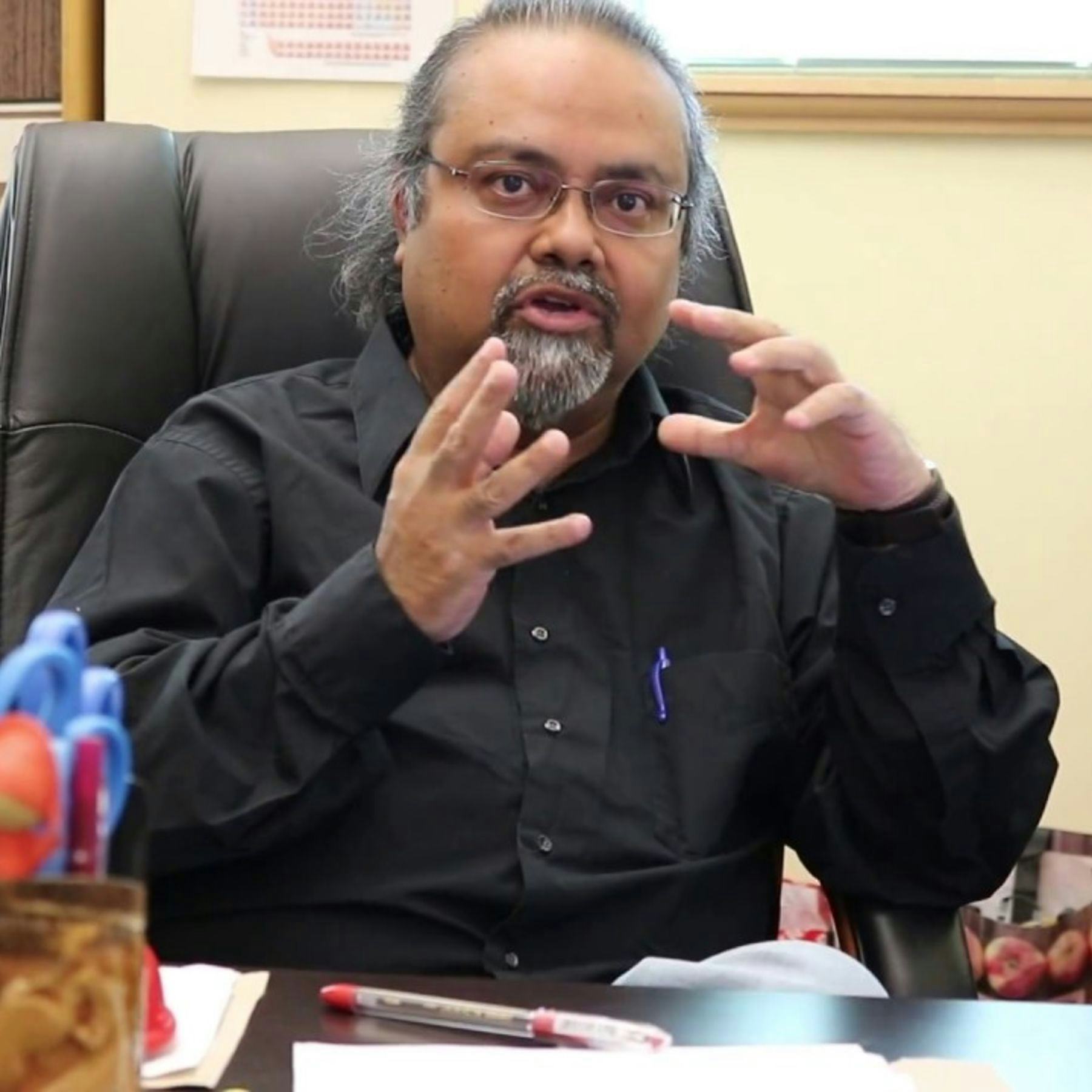 Professor Dibyendu Sarkar sitting at his desk explaining a concept
