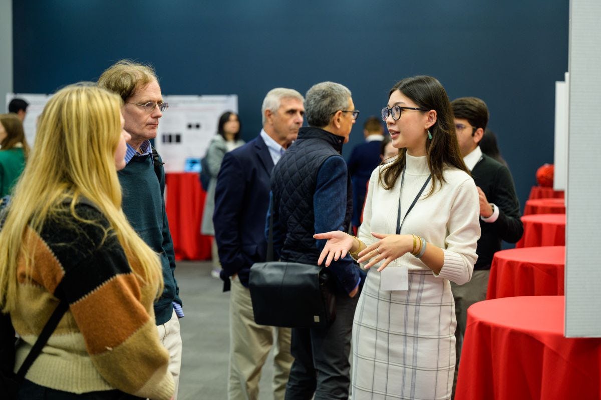 A female student discussing research with attendees at the SIAI Relaunch event