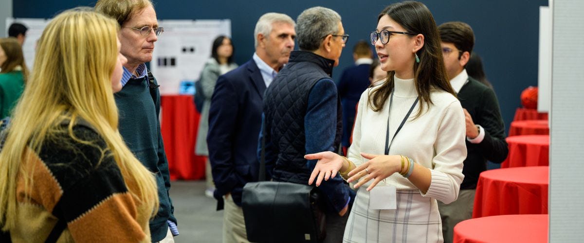 A female student discussing research with attendees at the SIAI Relaunch event