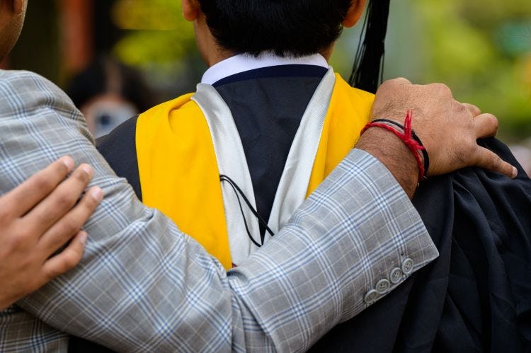 Hand is placed on a graduates shoulder