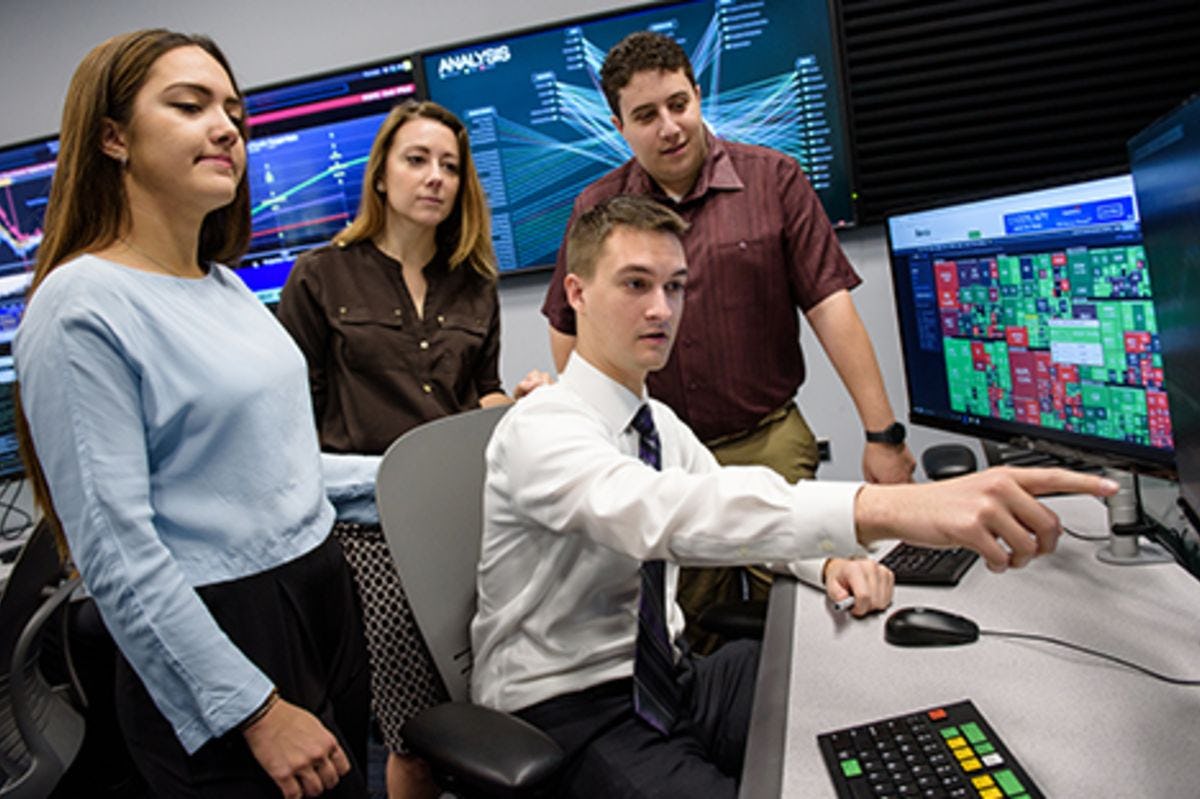 Two male and two female students work collaboratively with data visualization technology in a Stevens lab.