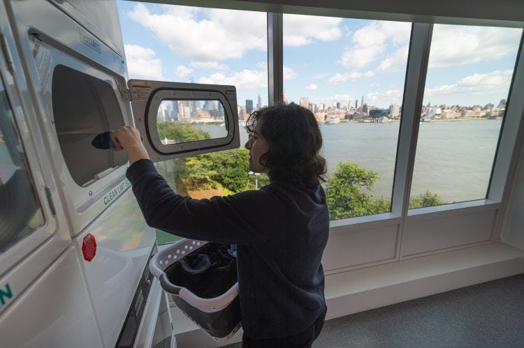 Student gathers laundry with amazing view of New York city behind.