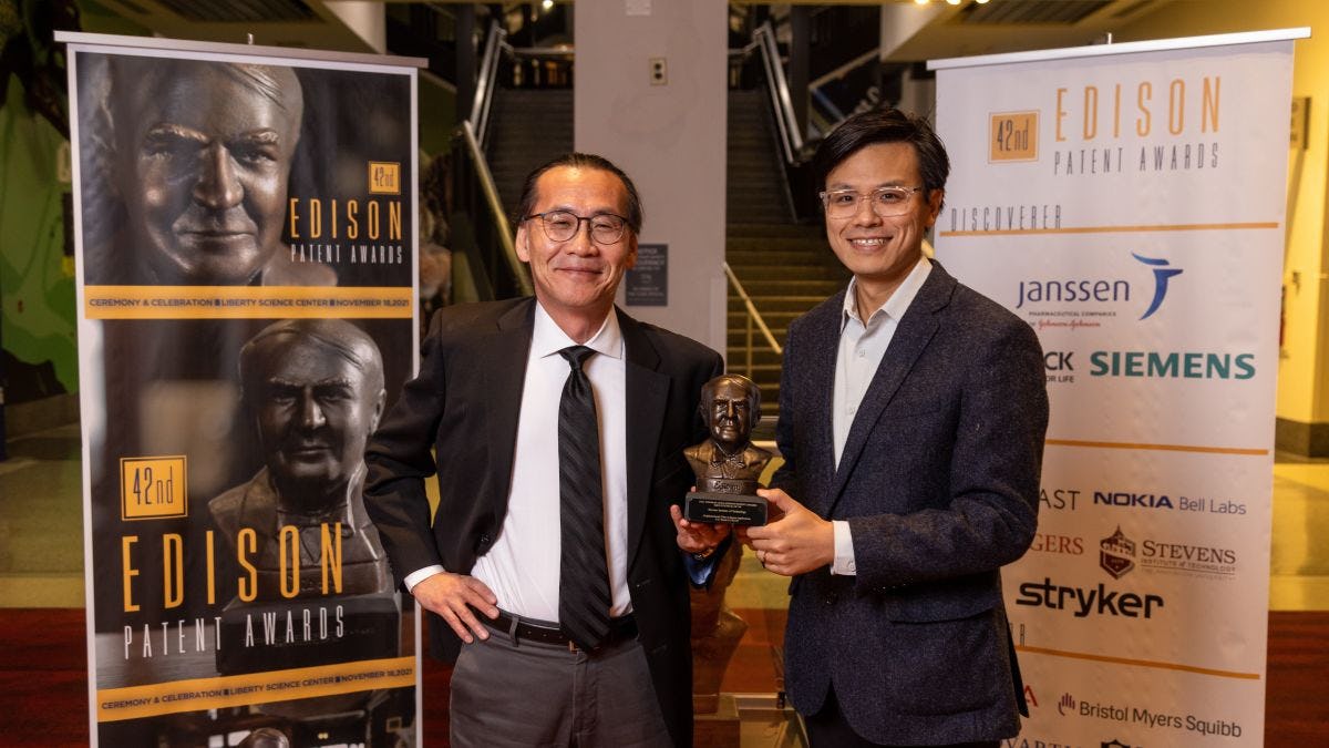 Two men, one holding a trophy, at Edison Patent Awards ceremony