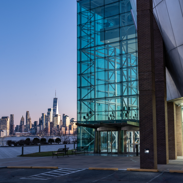 The Babbio Center with part of the New York City skyline in the background at dusk