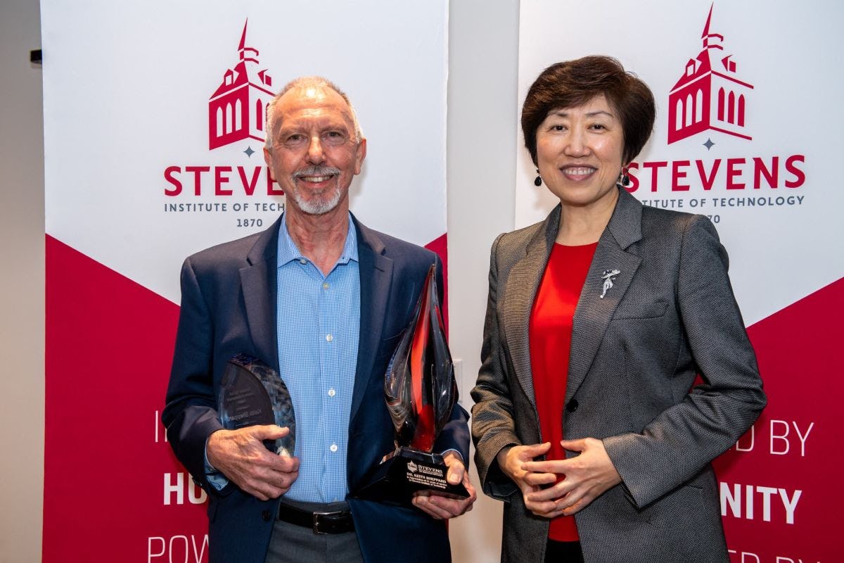 Emeritus Professor Keith Sheppard holding faculty awards, standing next to Dean Jean Zu