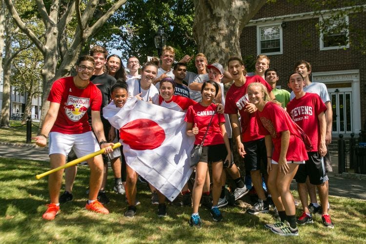 Group of students wearing red and holding a Japan flag outside