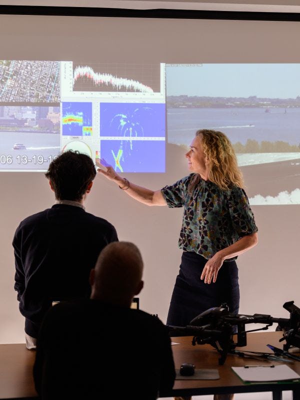 Intructor gestures to projected images of port security in class.