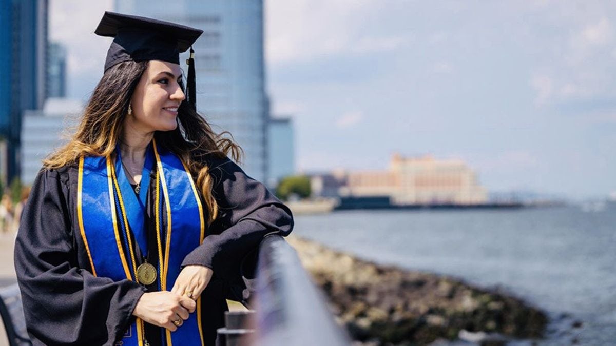 Fatine Zaaj along the Hudson River, dressed in her cap and gown. 