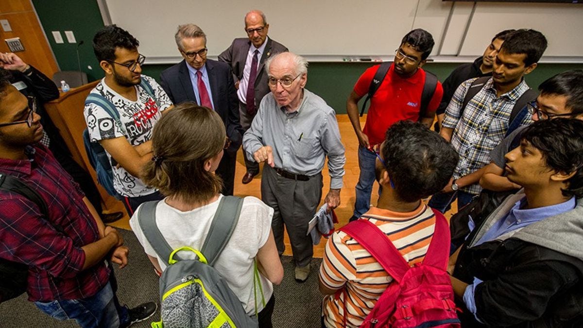 Students surround Josh Weston in a lecture hall after his talk.