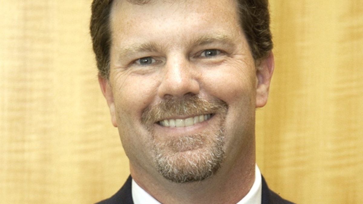 Close up headshot of Thomas A. McDermott Jr., Deputy Director of SERC at Stevens, wearing a black suit, white collared shirt, and blue tie. 