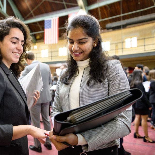 A female recruiter (left) at the internship fair chats with a female student as they go over her resume
