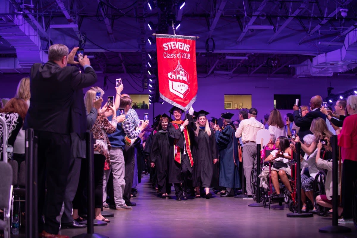 Students enter the arena led by the Class of 2018 banner