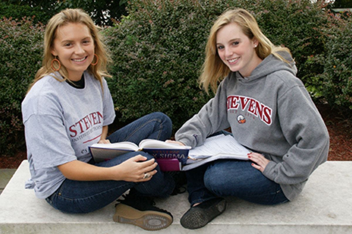 Two women studying outdoors on the Stevens campus.