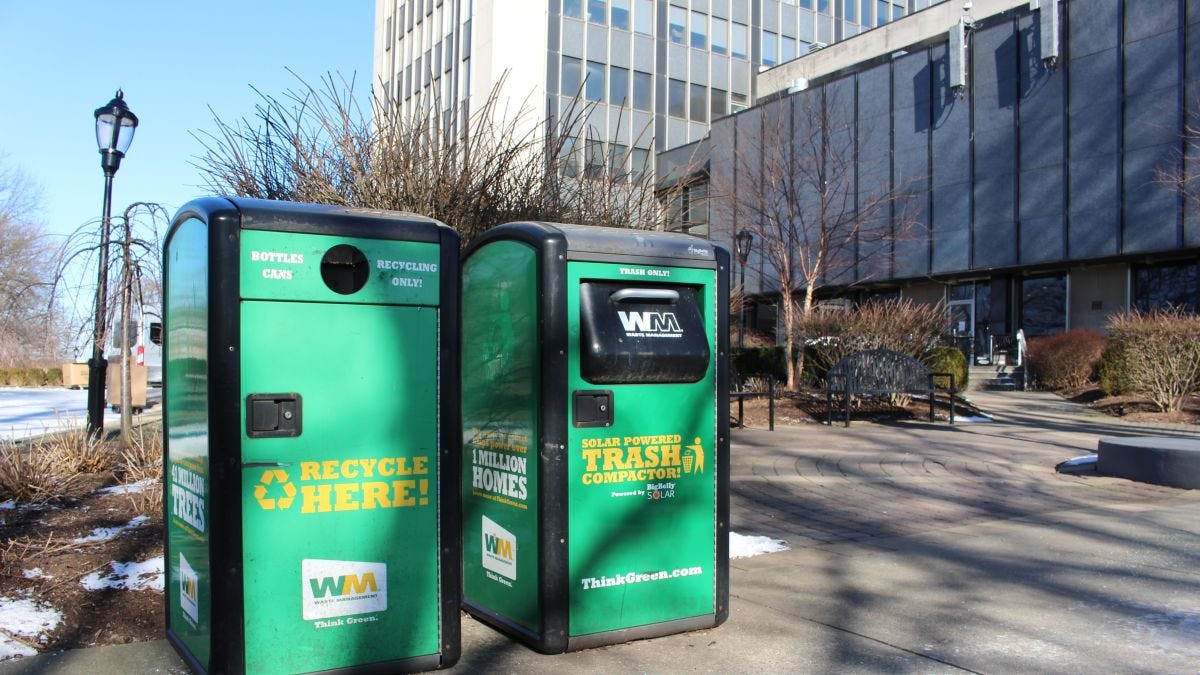 Two green solar trash compactors outside the Wesley J. Howe Center on the campus of Stevens Institute of Technology