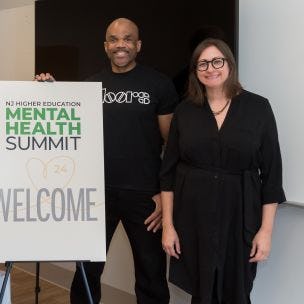 Three people posed in front of the Mental Health Summit sign