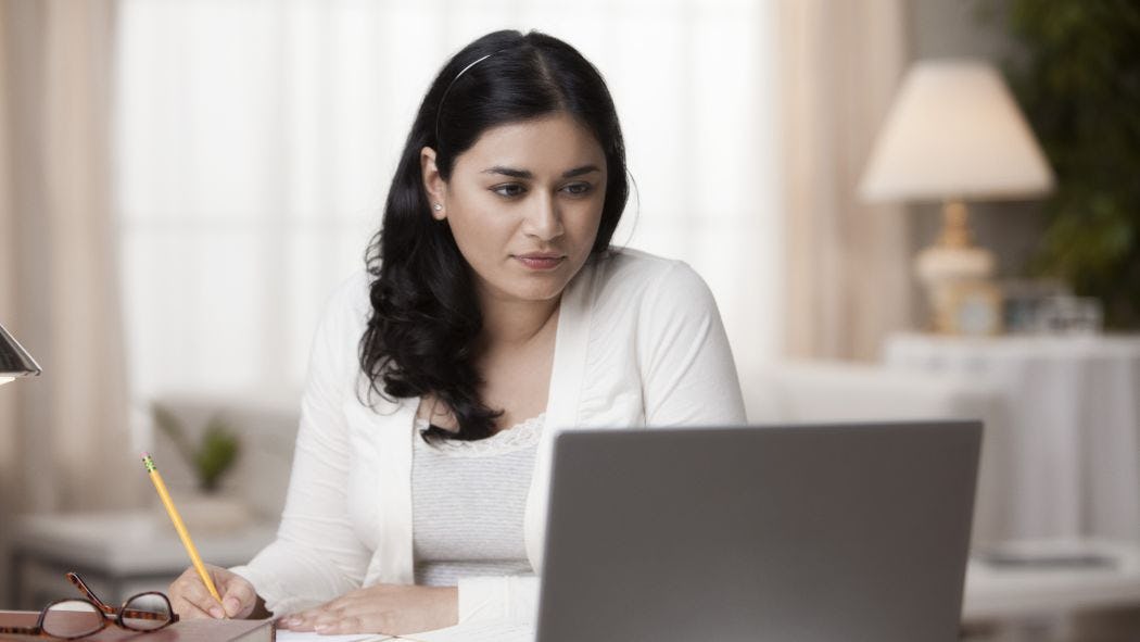 woman taking notes while looking at computer
