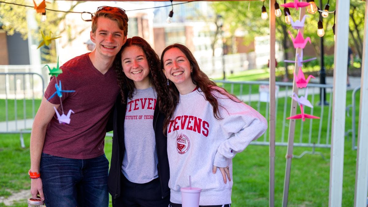 Three students smile in Stevens gear