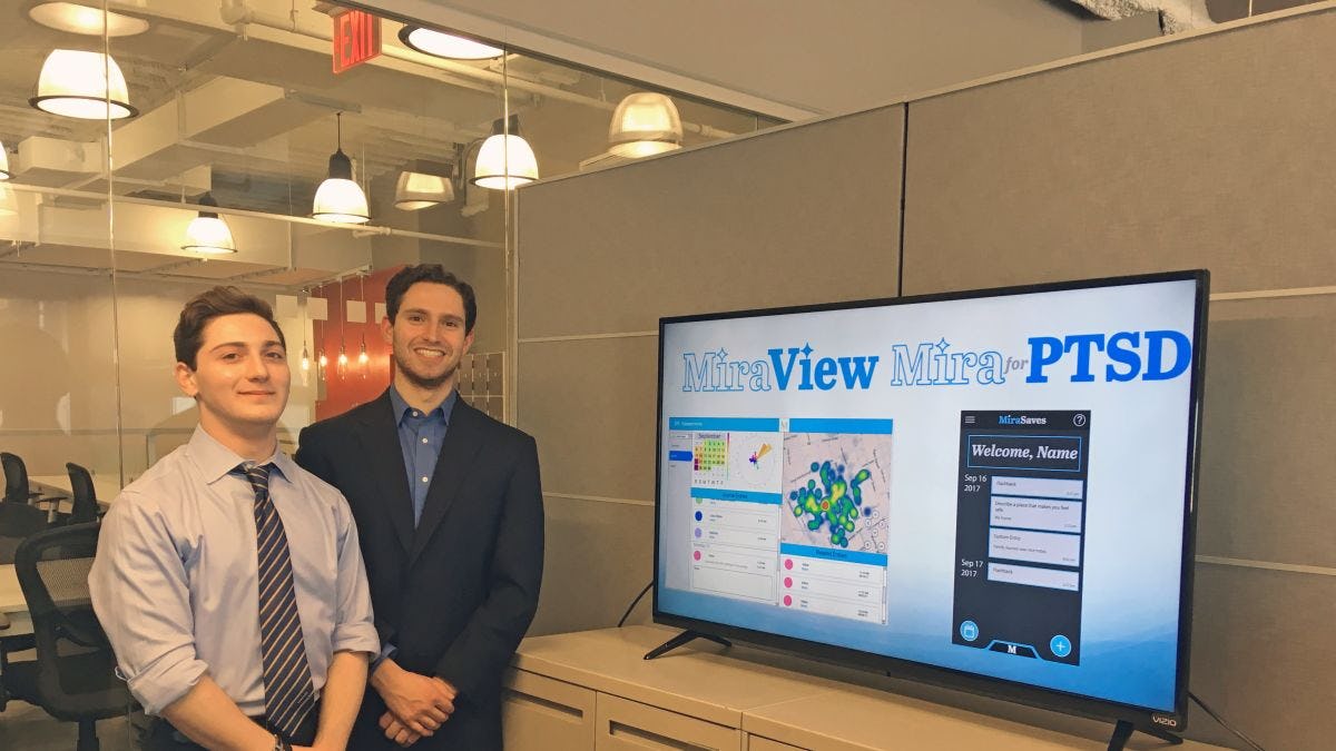 The two students behind MiraView in the Stevens Venture Center alongside a monitor showing their app's capabilities.