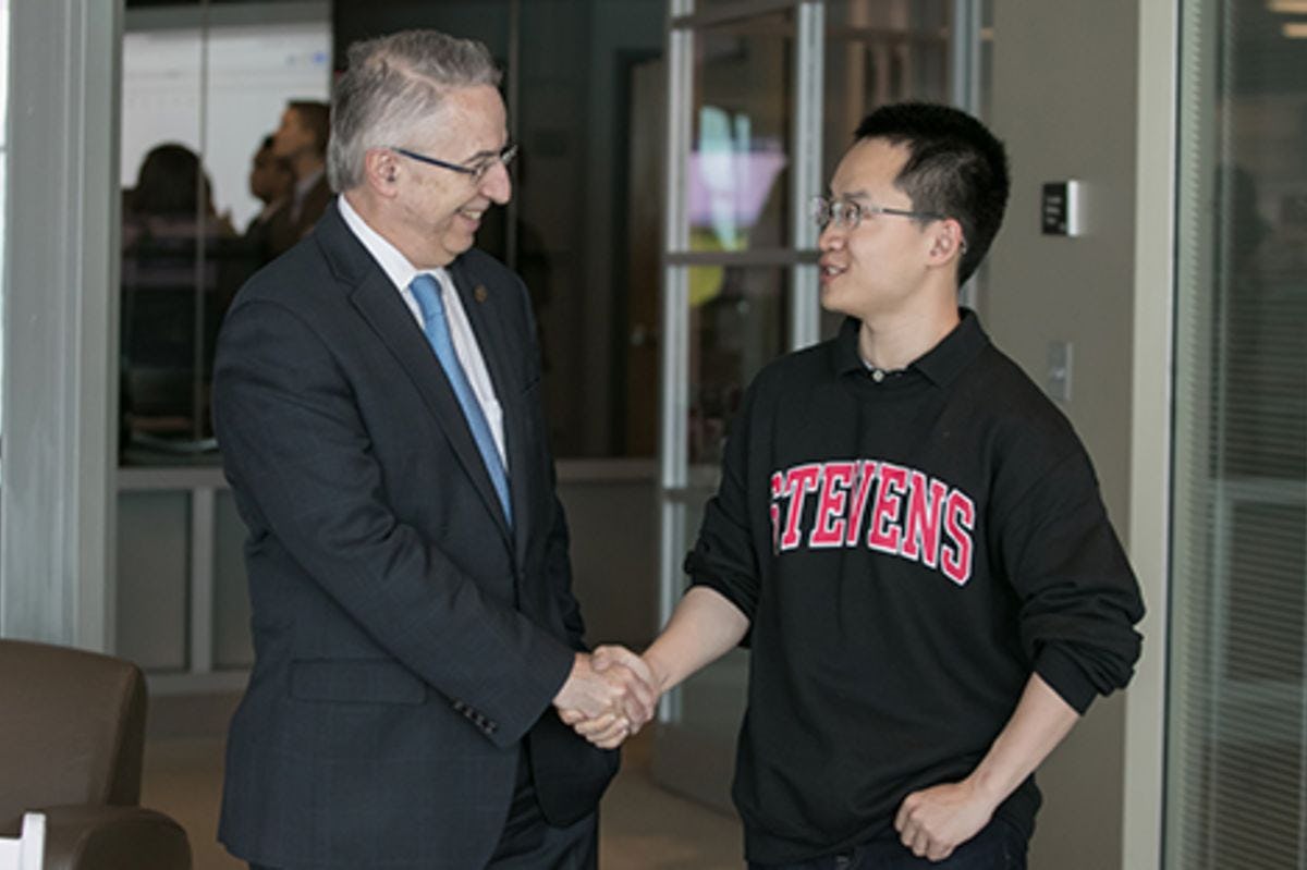 Gregory Prastacos shaking hands with Bruce Zhang at the Babbio Center at Stevens.