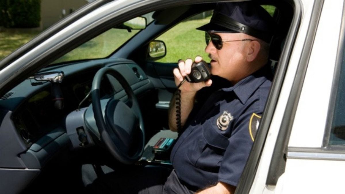 image of policeman talking on radio in police car