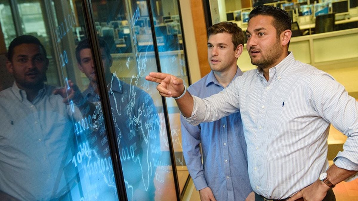 Two students comparing visualizations on a touchscreen in the Babbio Center at Stevens.