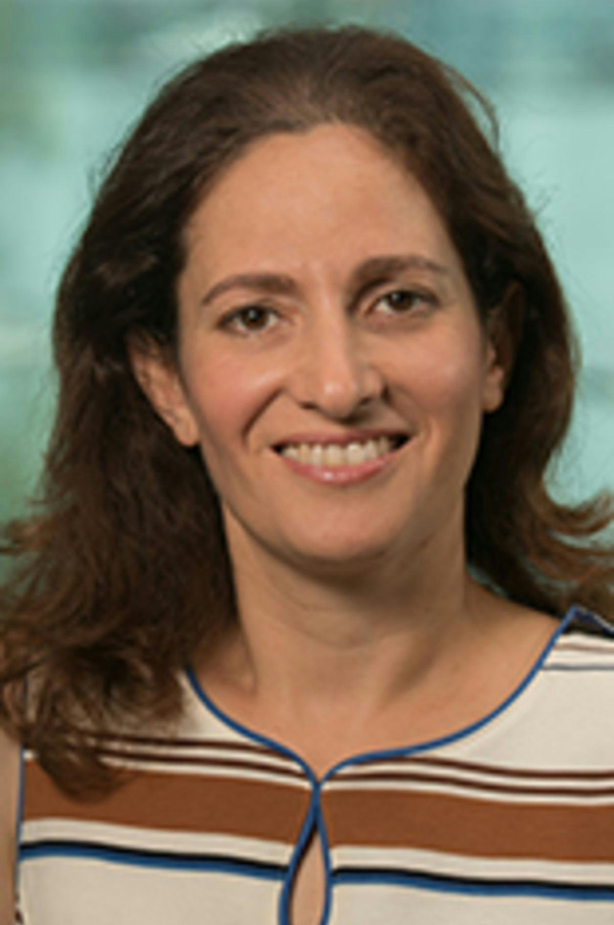Headshot of Dr. Joelle Saad-Lessler in a striped dress with the Manhattan skyline in the background.