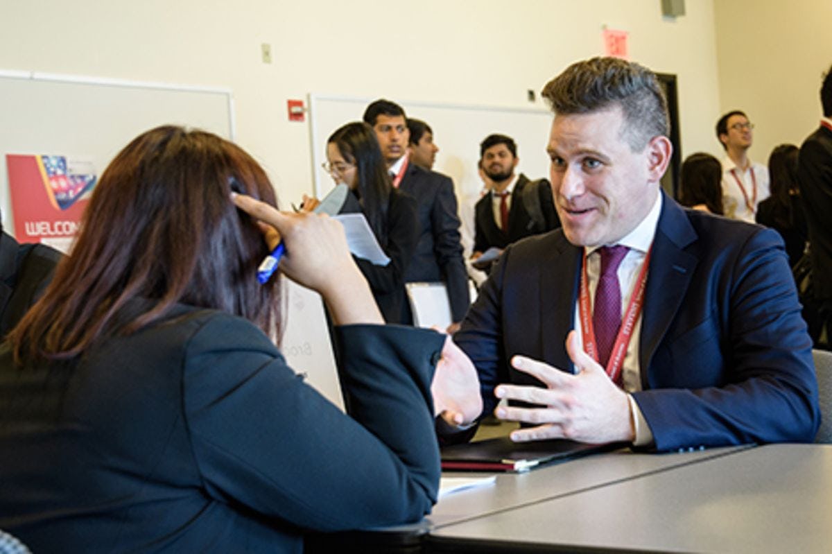 A male student gestures to a female recruiter on the Stevens campus.