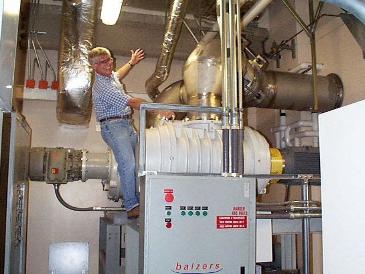 Photo of Ed Whittaker straddling a large vacuum pump