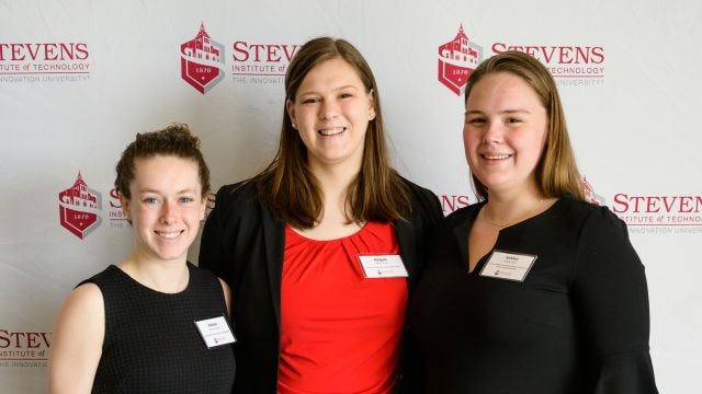 Three female students smile at scholarship event