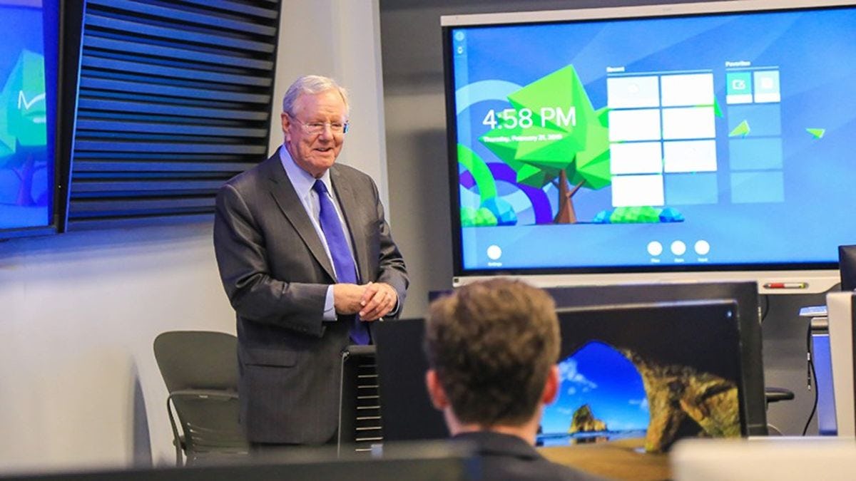 Steve Forbes talks to students in the Hanlon Lab. A number of screens and Bloomberg terminals can be seen.