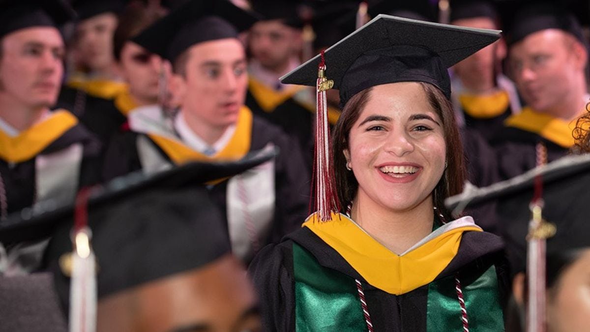 A female student in a crowd of classmates at commencement in 2019.