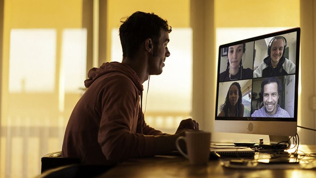 A student in a home office communicates with four classmates on his computer via Zoom.