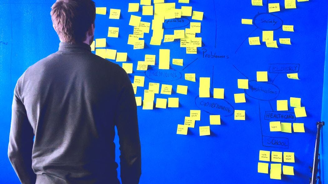 Man standing in front of board full of post-it notes