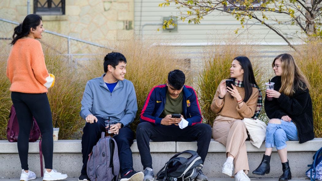 Group of students having a conversation on a bench outside Babbio Center.